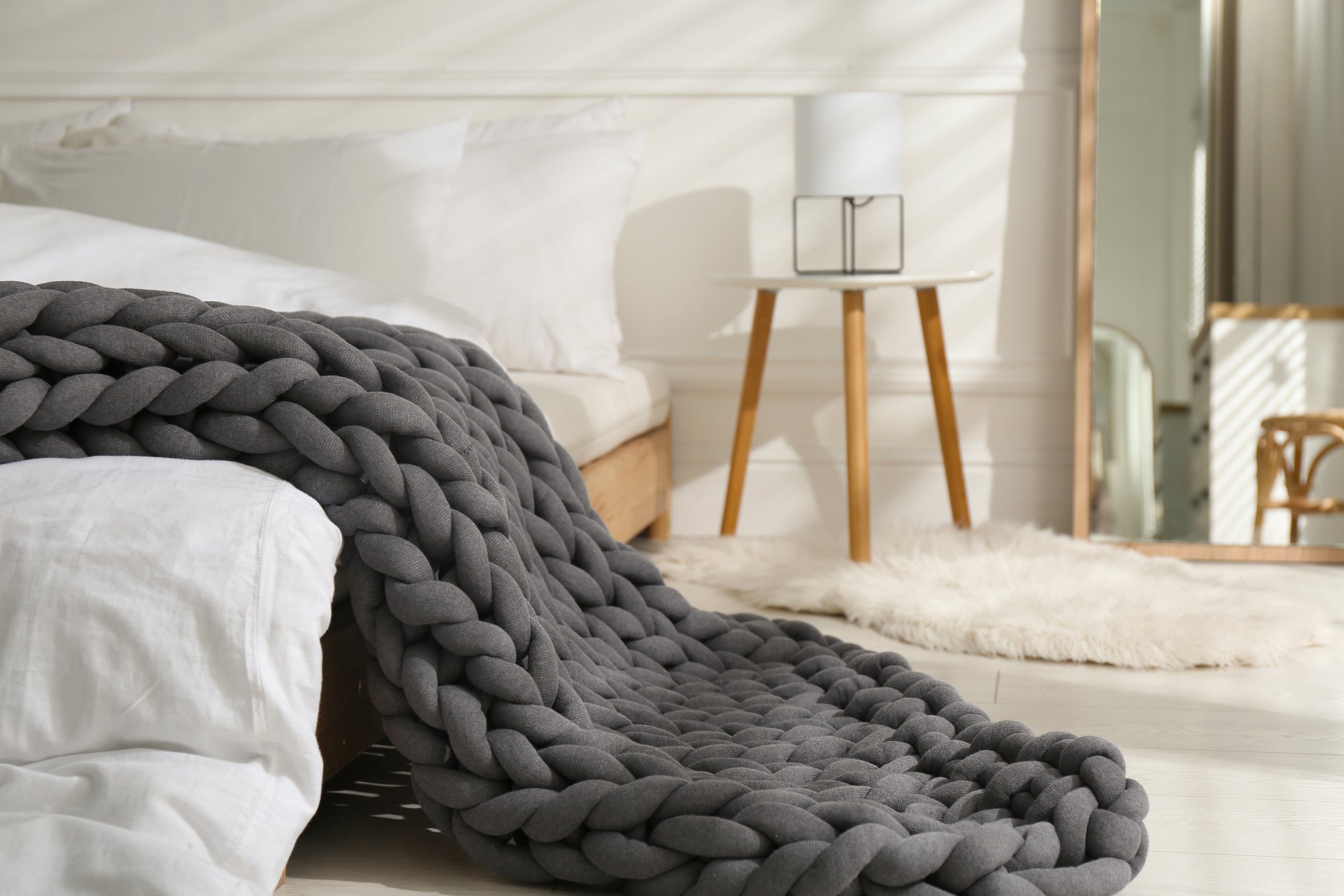 BloomKnit chunky cotton weighted blanket in charcoal gray on white bedding in modern bedroom setting