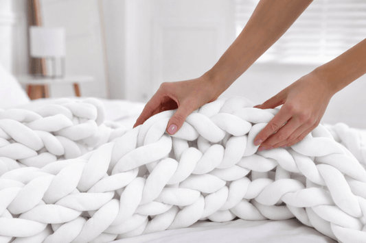 Luxury chunky hand knit weighted blanket in white draped across a bed in a soft neutral bedroom, illustrating chunky knit vs fine knit weighted blankets for hot sleepers by Blanket & Bloom.