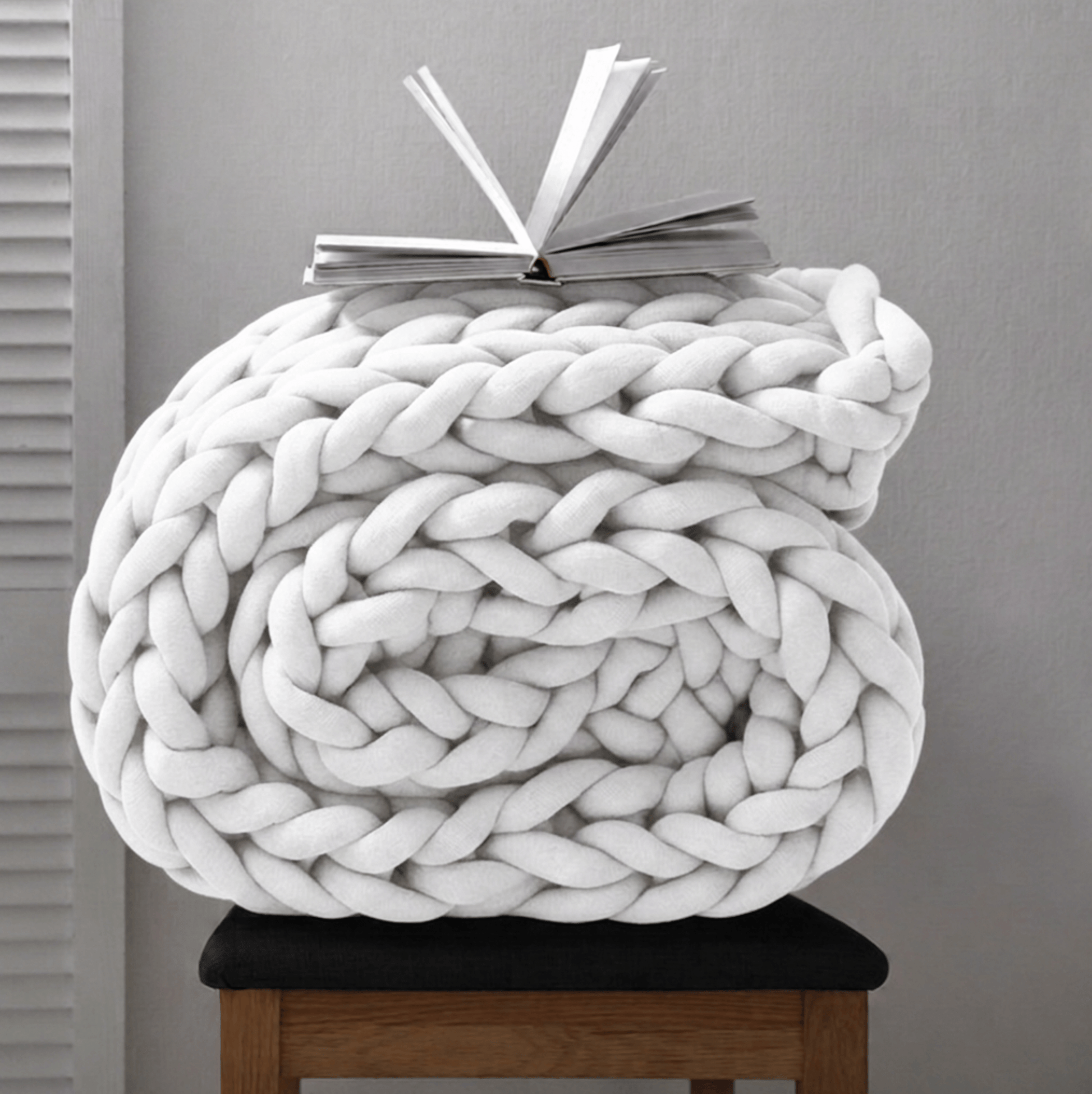 BloomKnit chunky cotton knitted weighted blanket in pure white folded on a wooden stool | pure white
