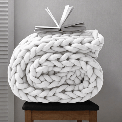 BloomKnit chunky cotton knitted weighted blanket in pure white folded on a wooden stool | pure white