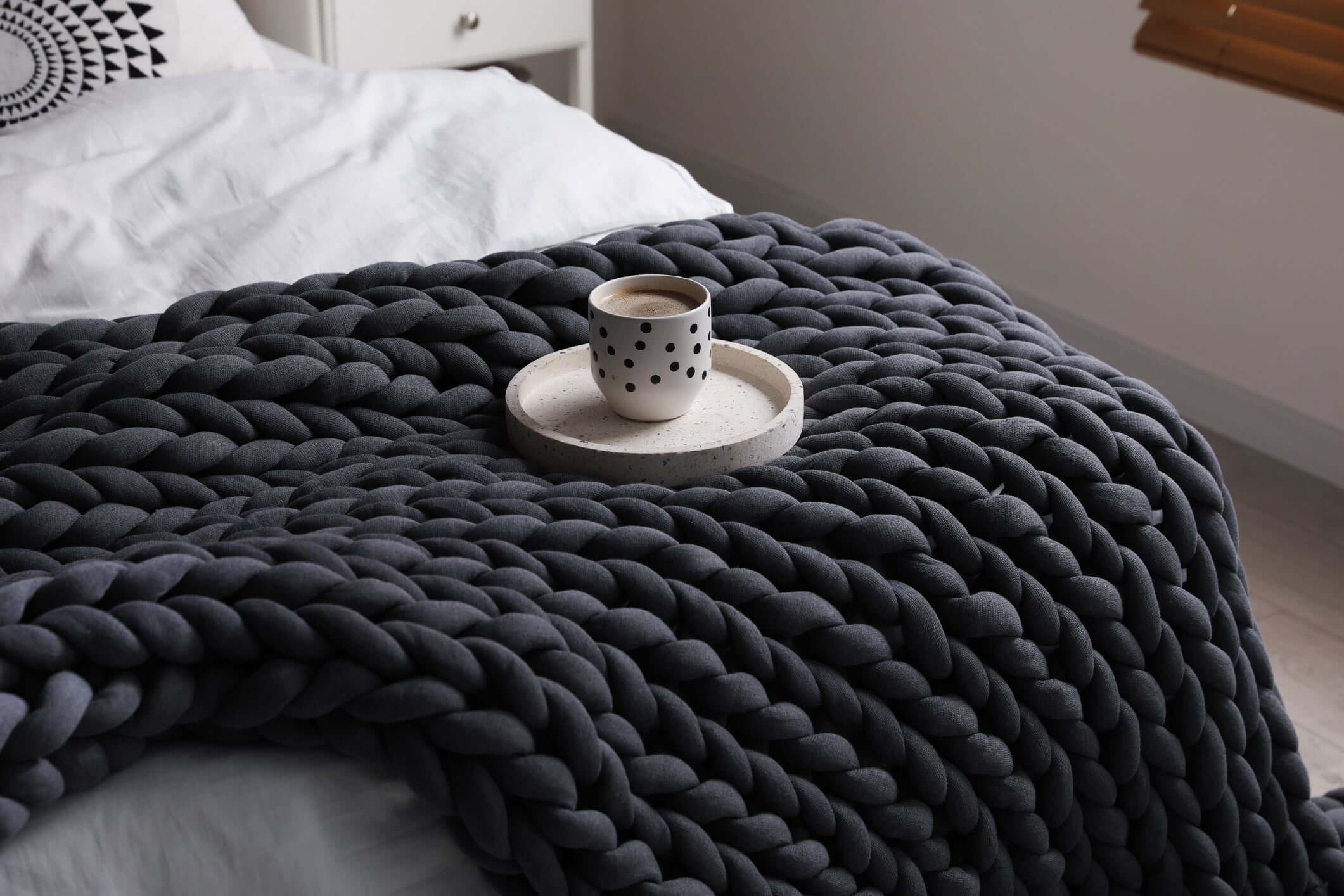 charcoal knitted blanket draped over a bed
