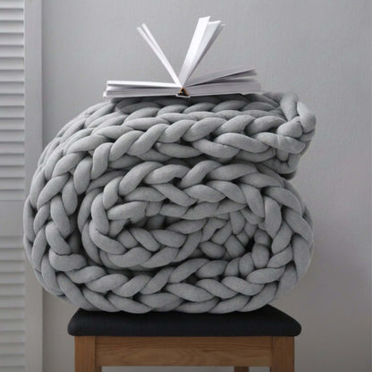 BloomKnit chunky cotton knitted weighted blanket in cloudstone, folded on a wooden stool | cloudstone