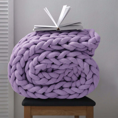 BloomKnit chunky cotton knitted weighted blanket in lilac veil, folded on a wooden stool | lilac-veil 