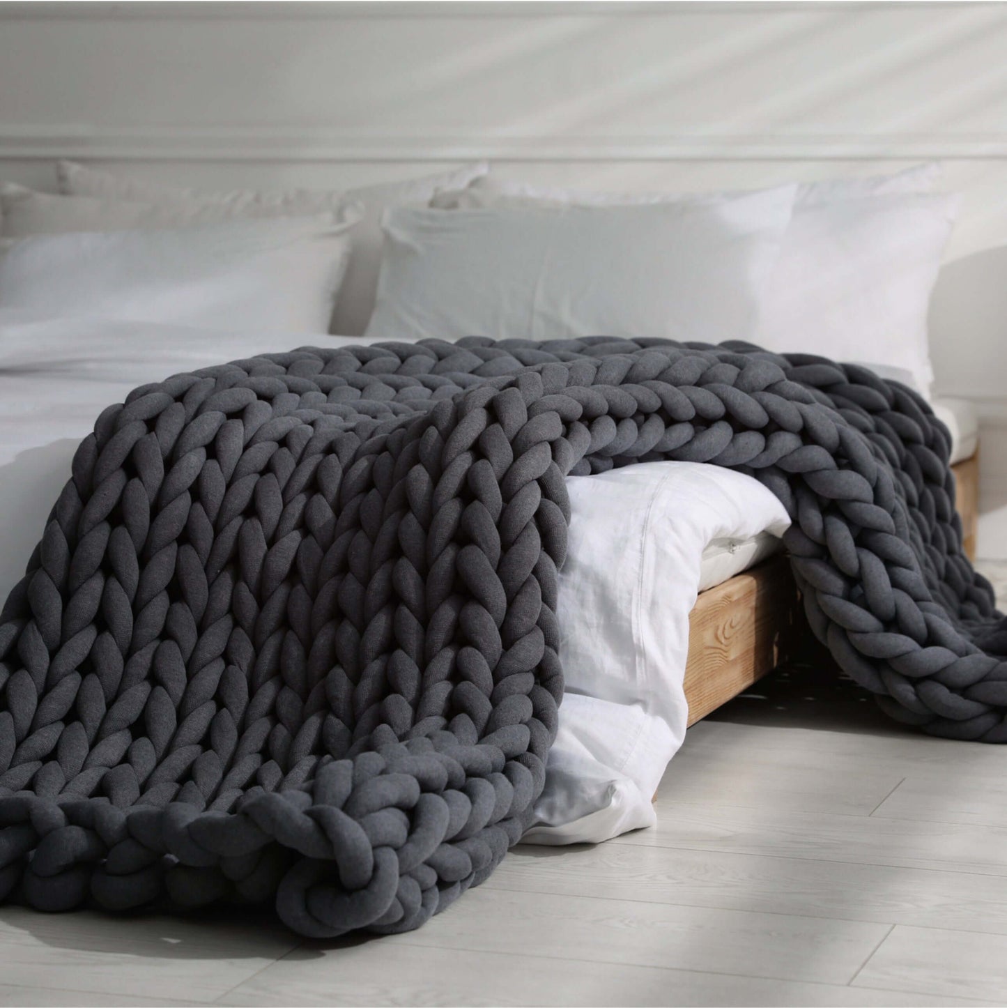 BloomKnit chunky cotton knitted weighted blanket in midnight ash, folded on a wooden stool | midnight-ash