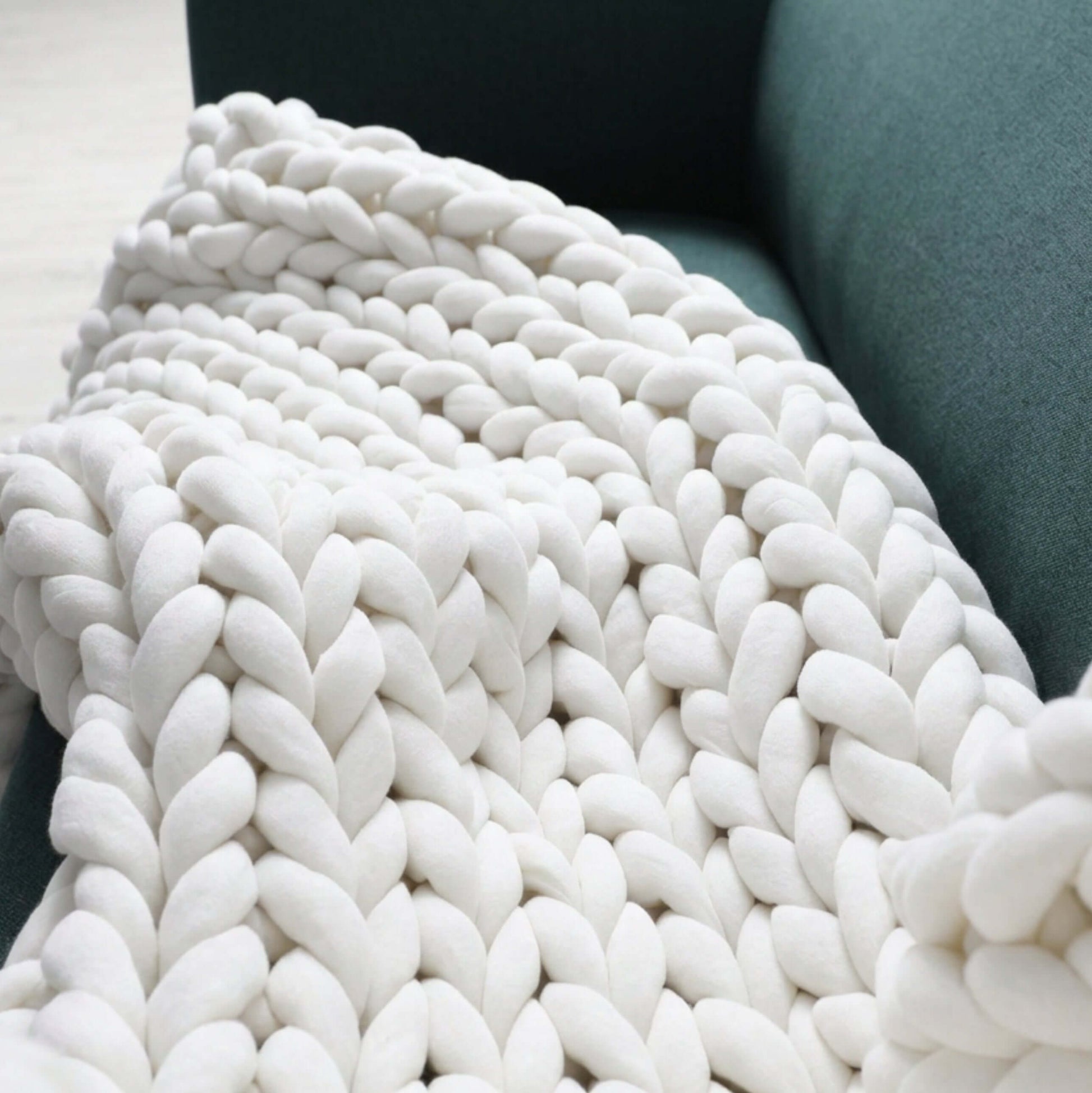 BloomKnit chunky cotton knitted weighted blanket in lilac veil, folded on a bed | pure white
