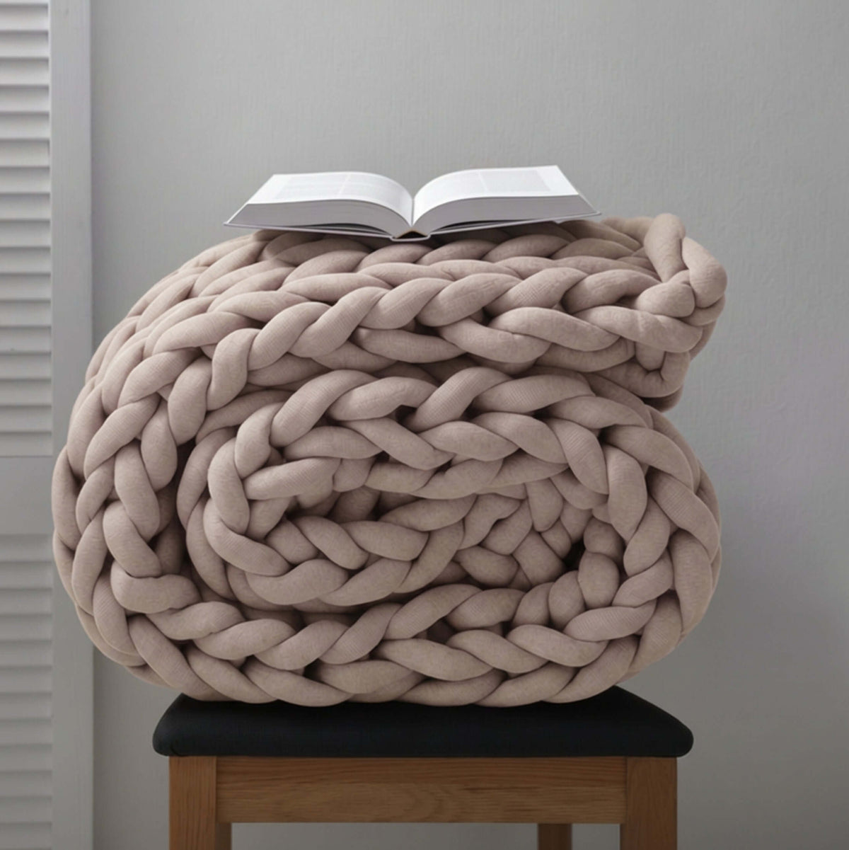 BloomKnit chunky cotton knitted weighted blanket in warm sand, folded on a wooden stool | Warm Sand™
