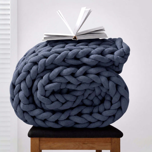 BloomKnit chunky knit weighted blanket in Slate, folded on a wooden stool | slate