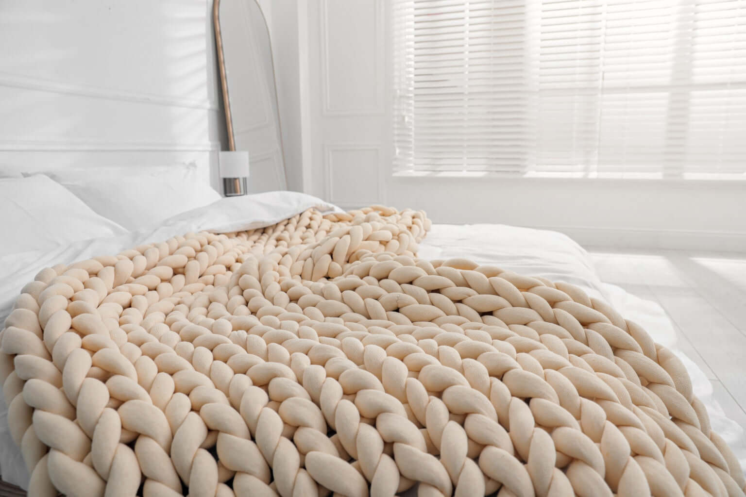 cooling chunky hand knit weighted blanket in warm sand on the bed
